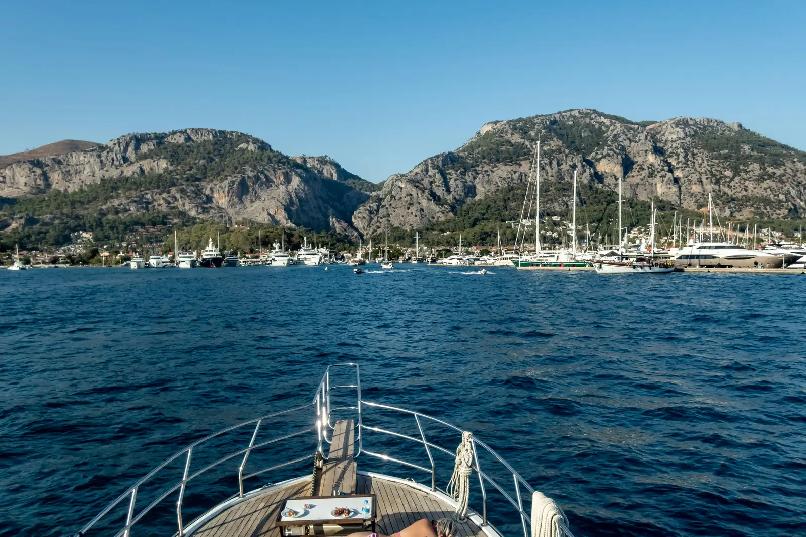 View from the bow of a marina, rocky mountains and deep blue water