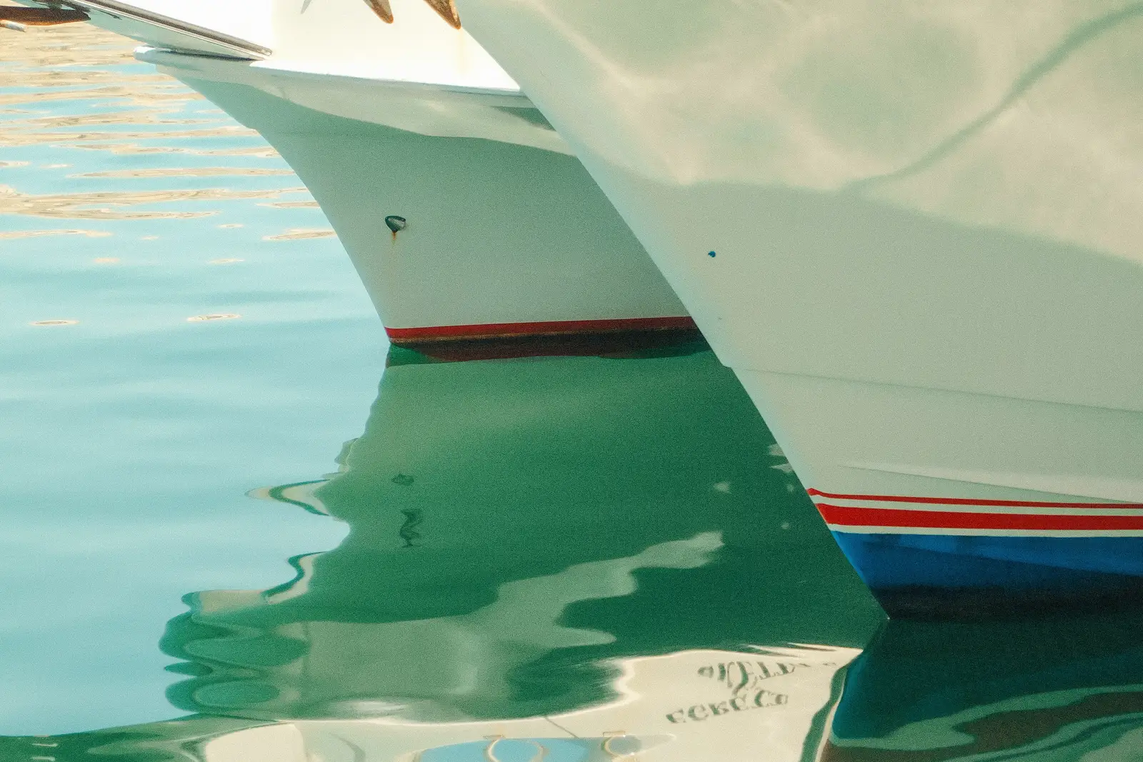 Bows of two boats tied side by side in turquoise water