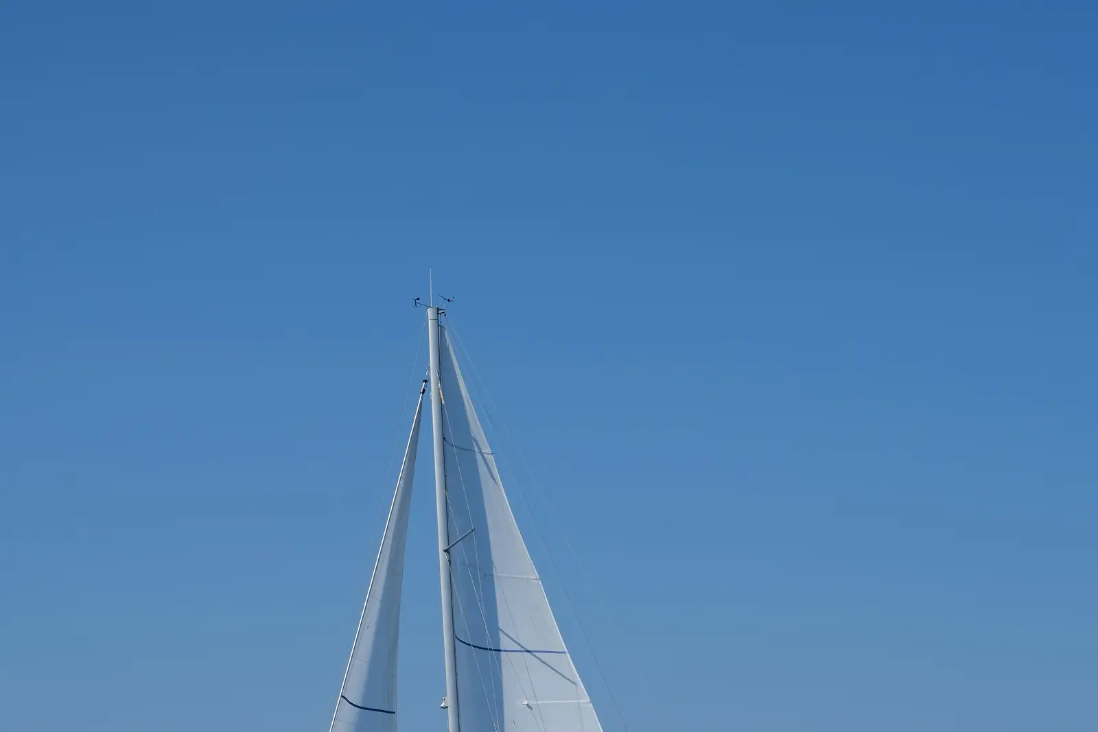 White sails reaching into a blue sky