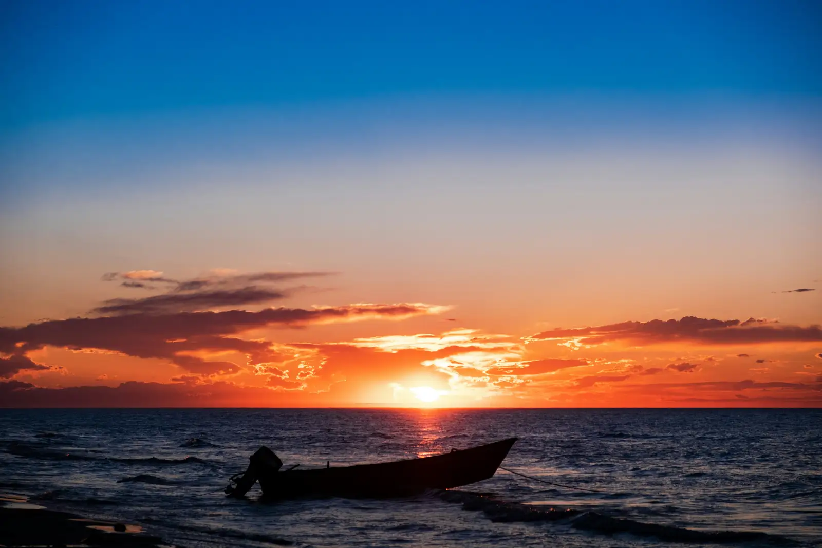 Red sky at sunset and a boat pulled up on the shore